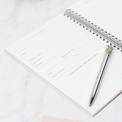 The IVF Planner open at the Clinic Information and Consultation page with a pineapple pen laying on top.