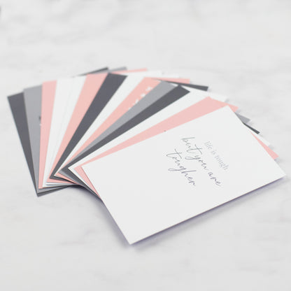 the cards are fanned out on a table, the card on the top of the fan says life is tough but you are tougher